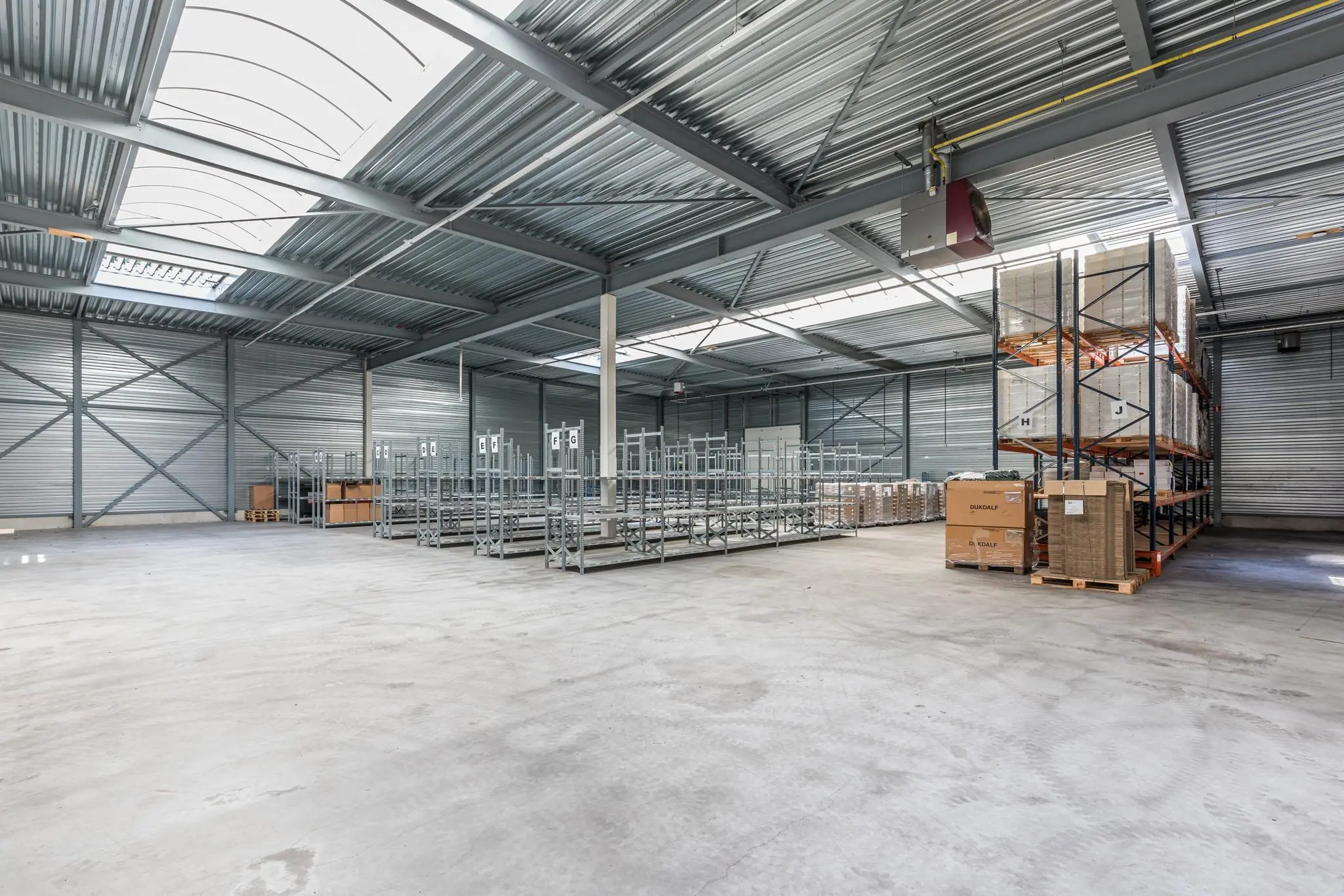 Ruim en licht industriepand aan de Laan Blussé van Oud-Alblas met stellingen en opgeslagen dozen.